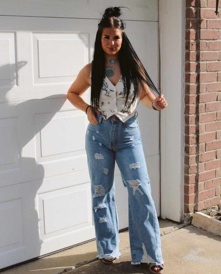 Girl wearing a sleeveless white button-up vest with blue high waisted distressed jeans