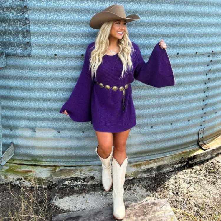 Naomi wearing a purple knitted sweater dress with white cowboy boots