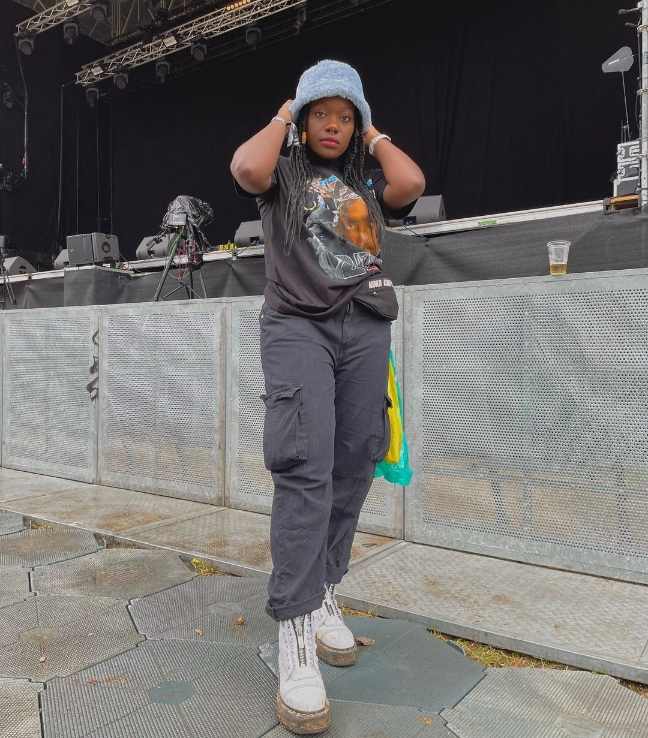 girl wearing a light blue bucket hat and an oversized graphic black T-shirt with black cargo pants