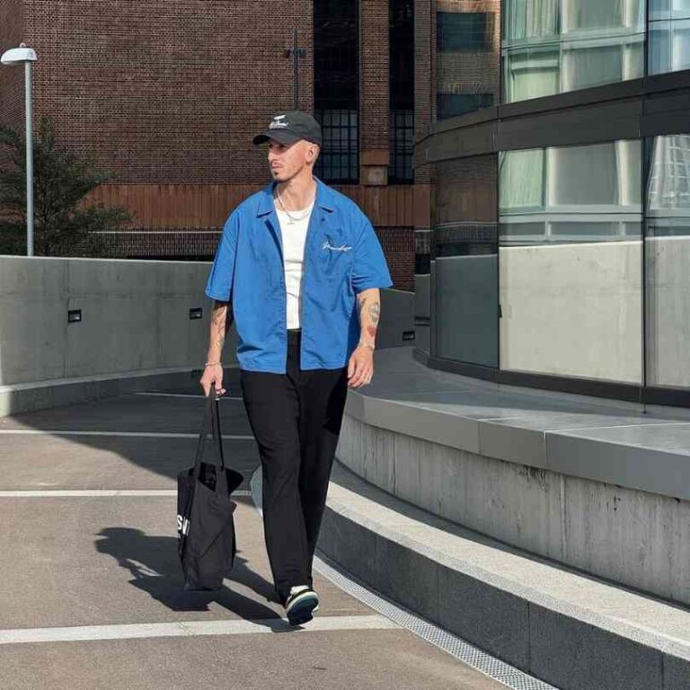 Guy wearing a blue short-sleeve button-up shirt over a white tank top with black straight leg trousers