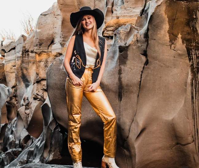 Audrey wearing a cream silk tank top with gold metallic pants