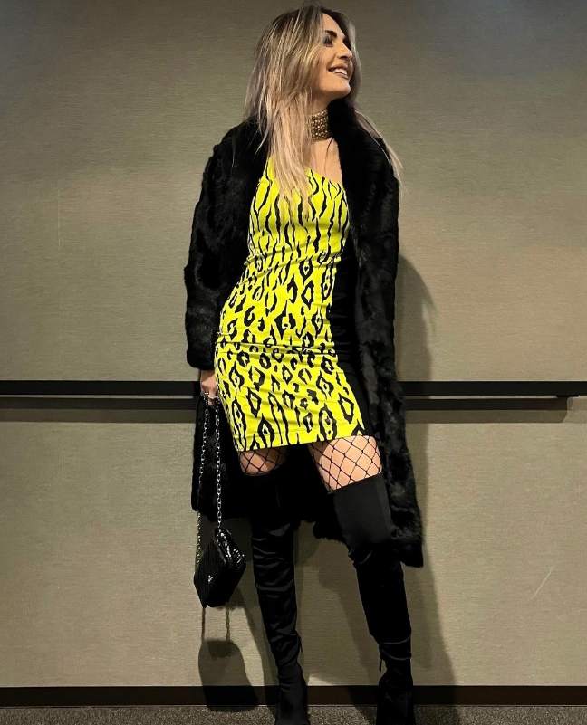 Giulia wearing a neon yellow animal print mini dress and a black fur coat