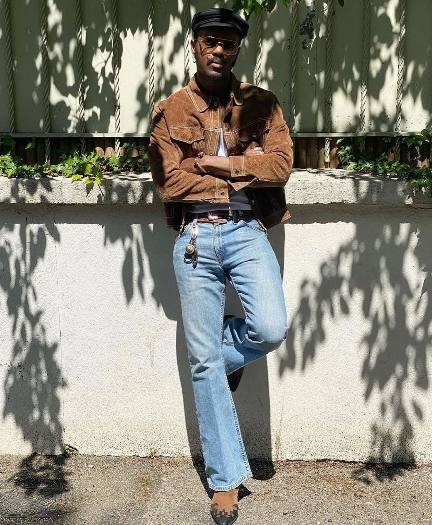 Guy wearing a brown suede jacket paired with a white t-shirt with blue straight leg jeans