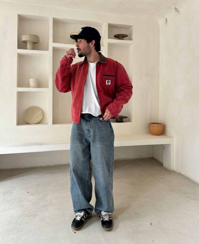 Guy wearing a red jacket with a brown collar over a wide t shirt and baggy jeans