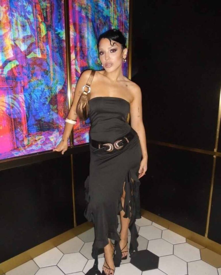 Niki wearing a black dress with cascading ruffles and a high slit