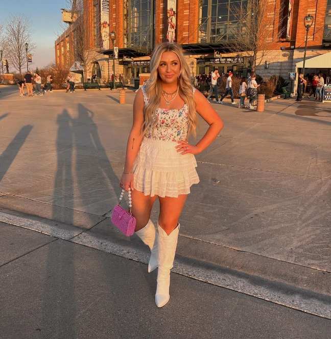 brooke wearing a white ruffled mini skirt and floral top with white cowboy boots