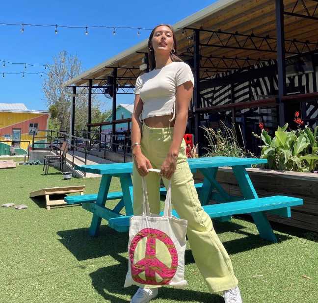 girl wearing a cropped, short-sleeve t-shirt in a light cream color with wide-legged pants in a light lime color