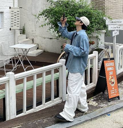 guy wearing an oversized, light blue denim button-up shirt over a white tee with white wide-leg cargo trousers