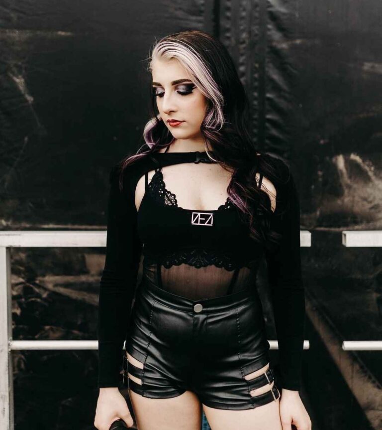 kasey wearing a black strappy crop top with lace and high-waisted black faux leather shorts