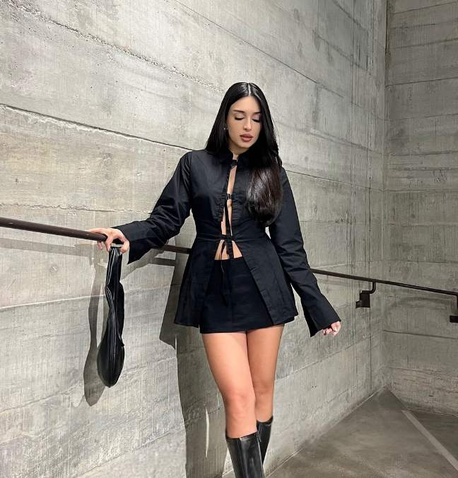 suellen wearing a long-sleeve black top with a high-waisted black mini-skirt