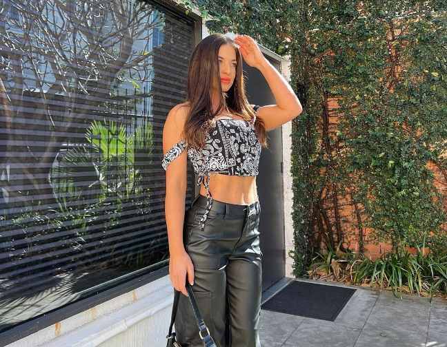 amy wearing A black-and-white bandana-style crop top with sleek black leather pants