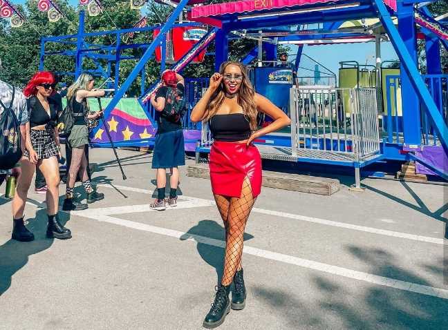 ellery wearing a black strapless top paired with a vibrant red leather mini skirt, and fishnet tights