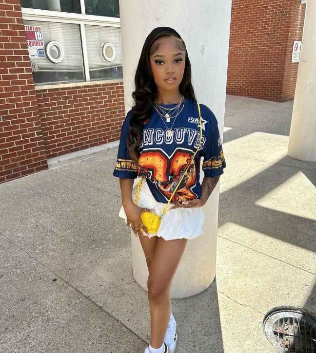 girl wearing oversized navy-blue graphic jersey top a white pleated mini skirt