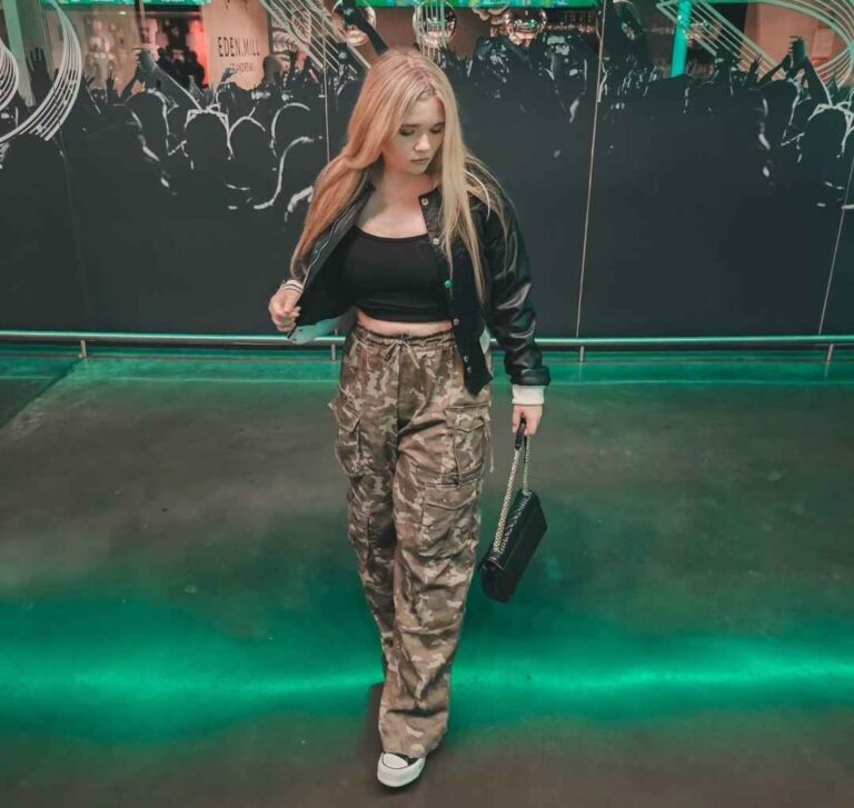 Girl wearing a black leather jacket over a black crop top with camouflage cargo pants