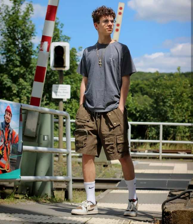 leon wearing A loose-fitting dark gray tee with khaki cargo shorts