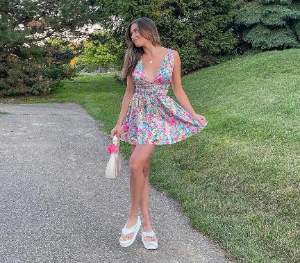 megan wearing A bright floral mini dress with a deep V-neck