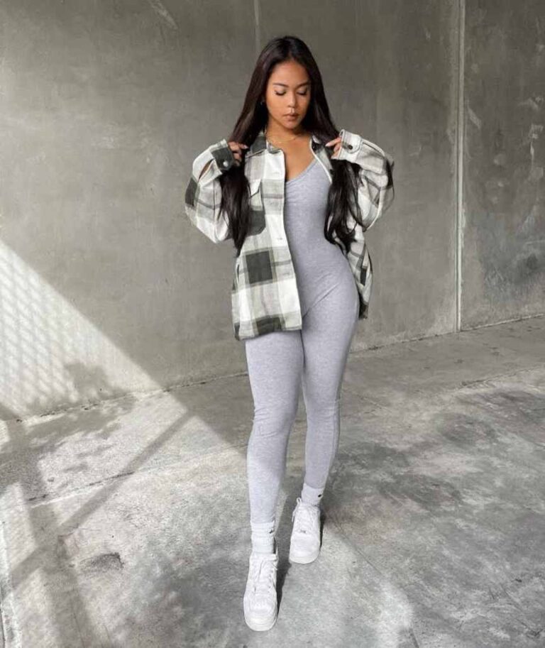 girl wearing A muted gray and white oversized plaid flannel over a fitted gray jumpsuit