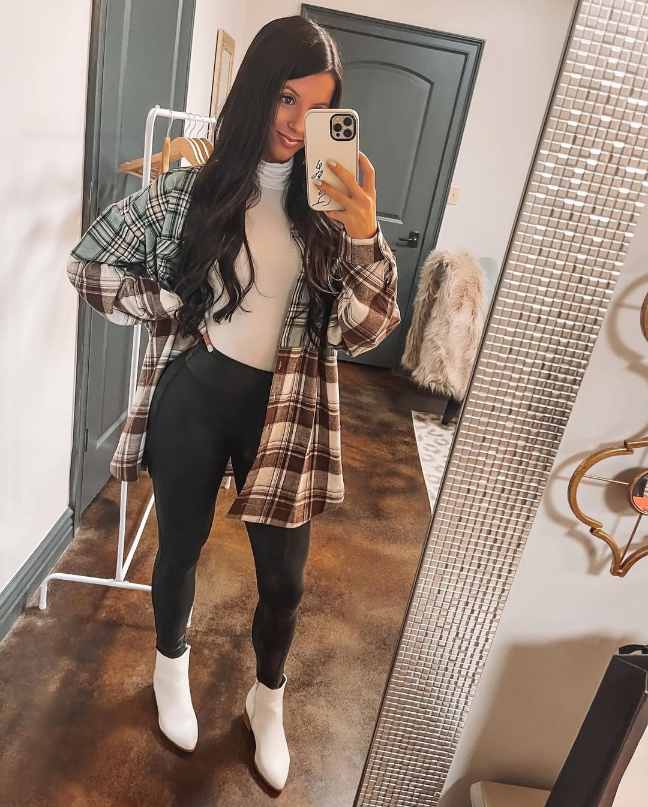 girl wearing An oversized flannel in neutral green and brown tones layered over a white turtleneck top with Black faux leather leggings