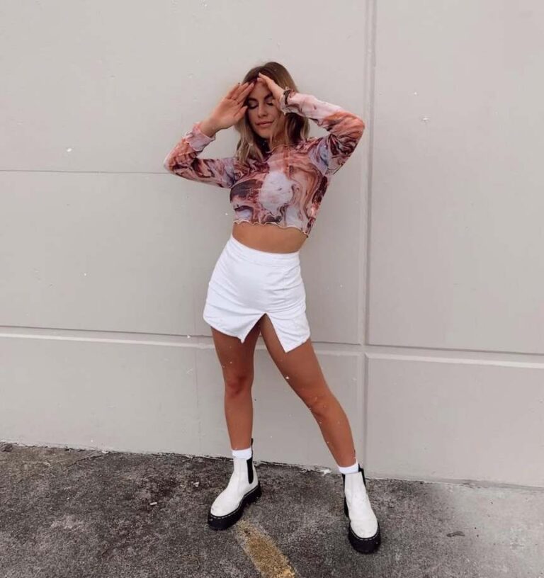 girl wearing a textured, marble-print crop top with white skirt and white doc martens