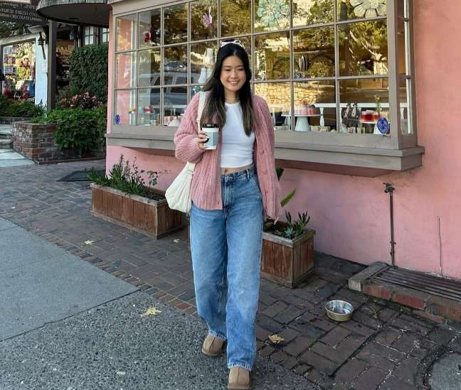 grace wearing a soft pink chunky knit cardigan with a white crop top with light-wash, loose-fitting, high-waisted jeans