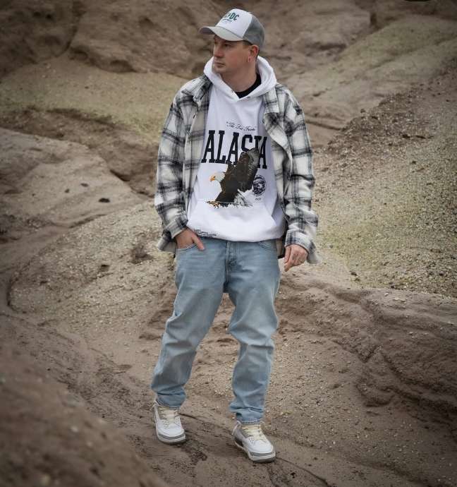 guy wearing A black-and-white plaid flannel over a bold white graphic hoodie with Light-wash relaxed-fit jeans