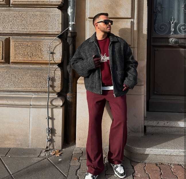 guy wearing a dark gray wool jacket with a layered over a burgundy crewneck sweatshirt with Straight-leg burgundy trousers