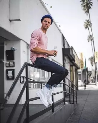 guy wearing a pastel pink long-sleeve shirt with dark wash jeans and white doc martens