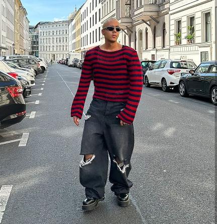 guy wearing a red and black striped sweater and oversized, distressed black jeans with platform Doc Martens