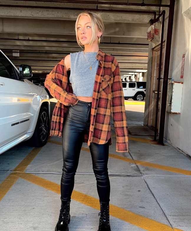 ileen wearing A burnt orange and red plaid oversized flannel over a fitted gray crop top with Black faux leather leggings