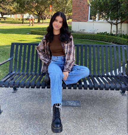 nicole wearing a fitted brown top with an oversized plaid shirt and relaxed high-waisted jeans paired with black platform Doc Martens