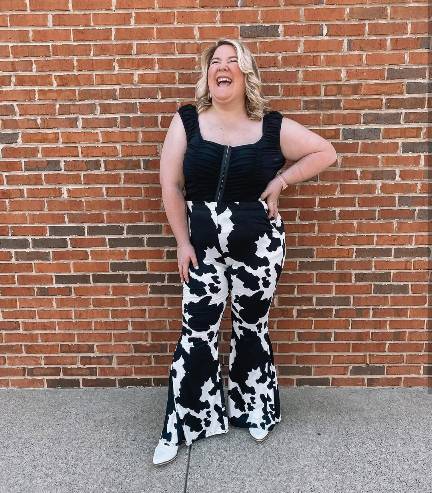 plus size girl wearing a black ruched top with cow-print flared pants