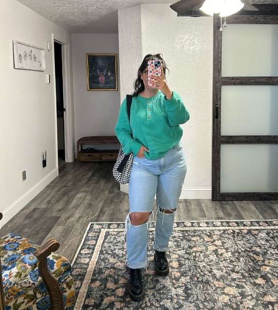 sidney wearing a bold green sweater paired with ripped light-wash jeans and doc martens