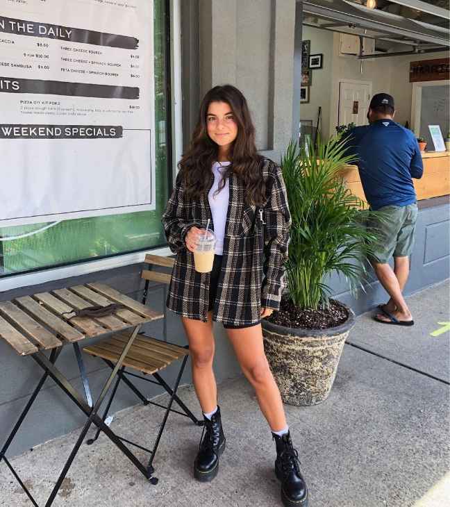 vivian wearing An oversized plaid flannel in neutral tones over a white fitted tee and Black high-waisted shorts