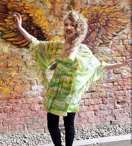 woman wearing a flowing green and yellow patterned mini-dress with dramatic bell sleeves